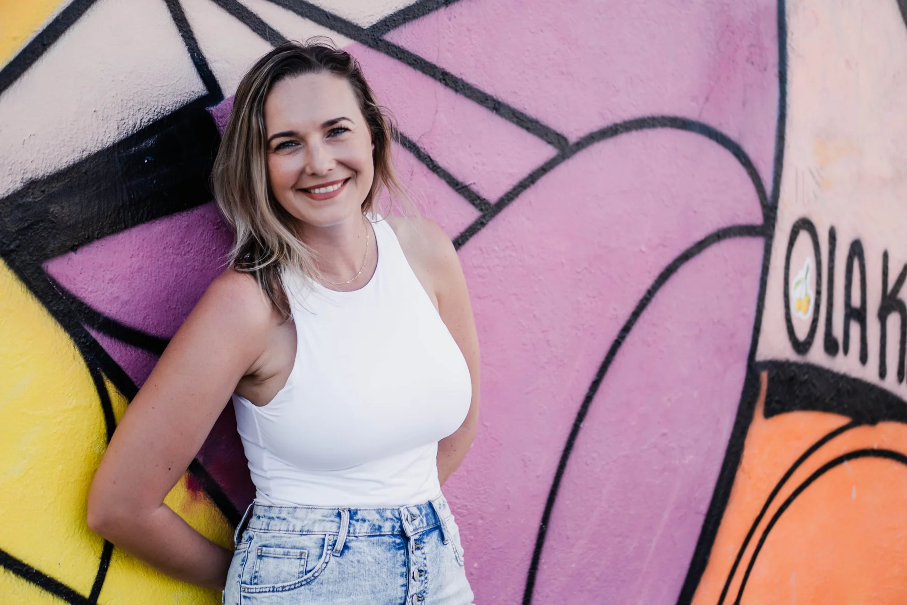 Kelley Rowe of WebInk Solutions standing beside a colorful Sarasota mural